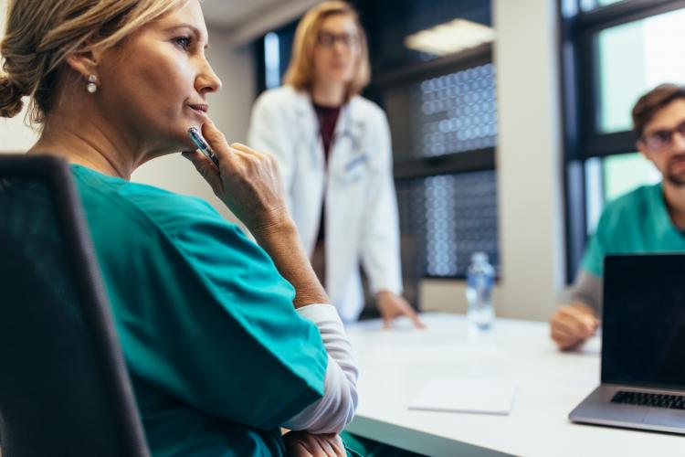 Nurse and doctor gather around a table for a meeting